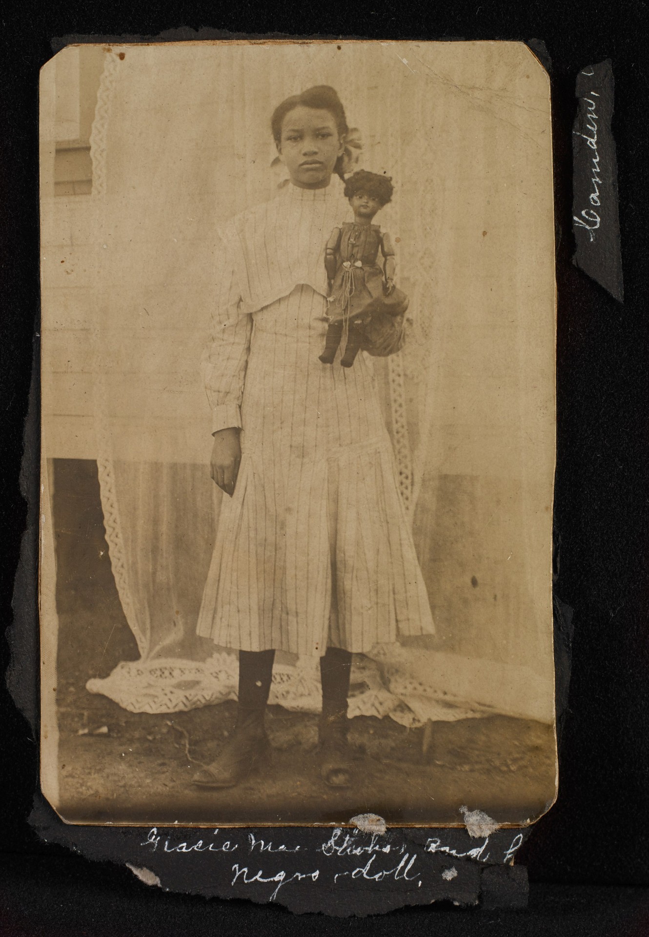Unidentified photographer, Gelatin silver print mounted on album page, Camden, AR, ca. 1910 Inscribed on page: “Gracie Mae [Hicks] and her Negro doll” and “Camden.”